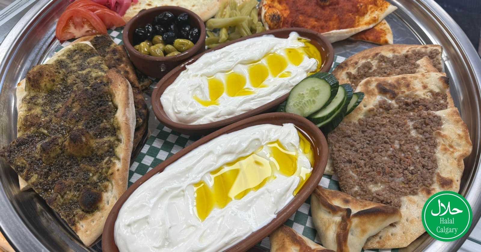 An Arabic breakfast tray at Well Bake: labneh with olive oil, za'atar and meat manakish, fatayer, olives and pickles