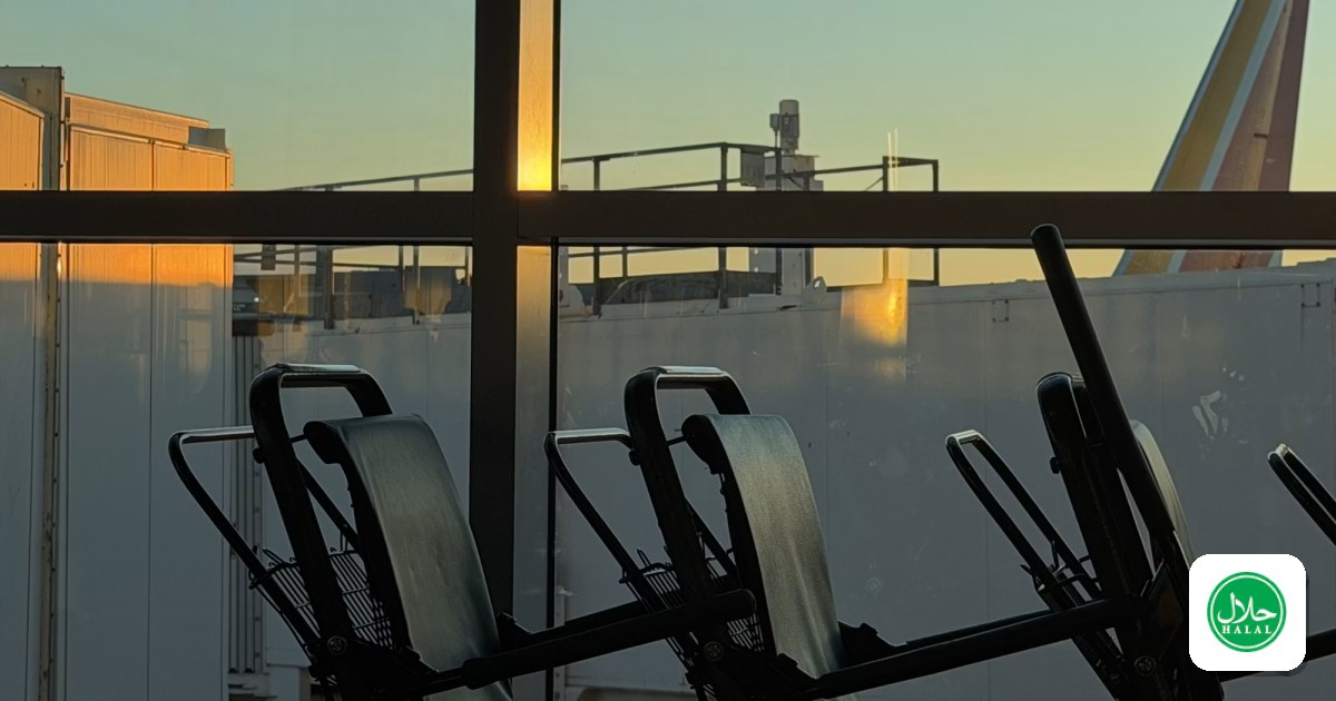 An airport gate at sunset, with an aircraft tail beyond the window
