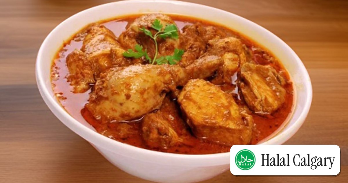 A bowl of chicken curry beside steamed rice
