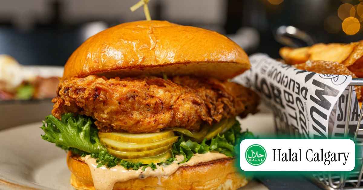A crispy chicken sandwich with pickles beside a basket of fries