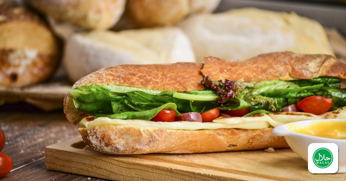 A submarine sandwich on a crusty roll with lettuce and tomato, on a wooden board